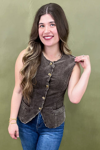Woman wearing a brown vest over a blue top against a green background