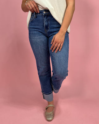 Person wearing blue jeans on a pink background