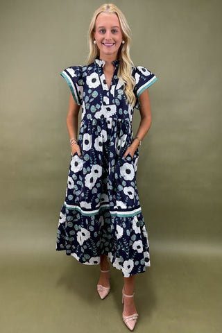 Woman wearing a navy floral dress against a green background