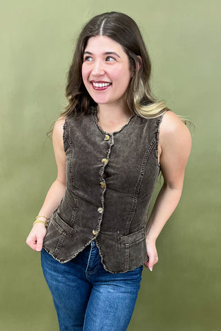 Woman wearing a brown vest over a blue shirt against a green background