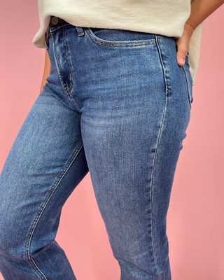 Blue jeans worn by a person on a pink background