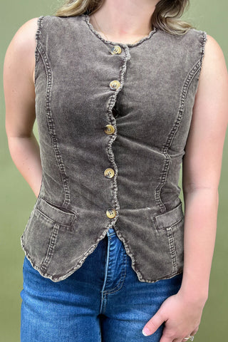 Denim vest with button details worn by a person on a green background