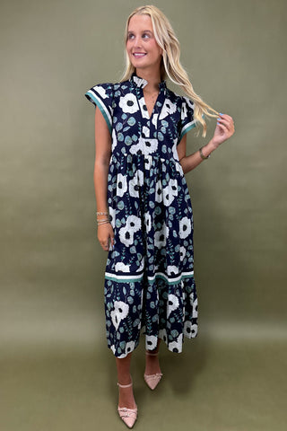 Woman wearing a navy floral dress against a green background