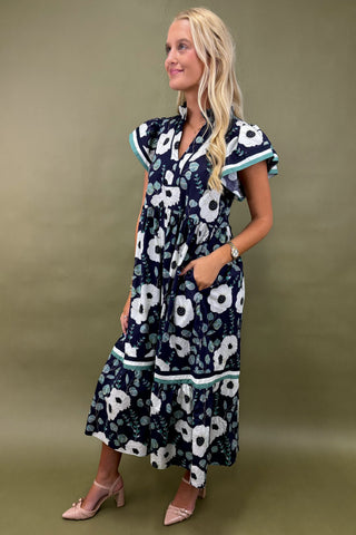 Woman wearing a navy floral dress against a green background