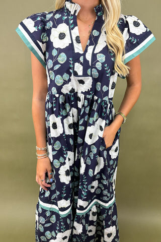 Navy floral dress worn by a person on a beige background
