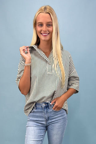 Woman wearing a striped shirt and jeans against a blue background