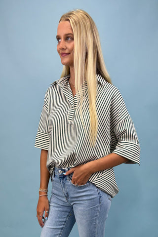 Woman wearing a black and white striped shirt and blue jeans against a light blue background