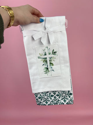 White fabric bag with floral design held by a hand against a pink background