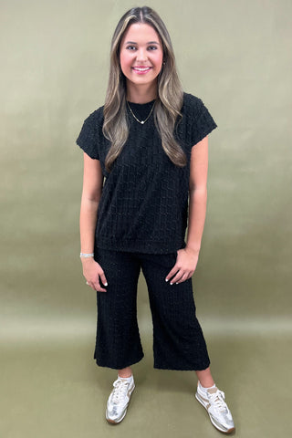 Woman wearing a black outfit with white sneakers against a beige background