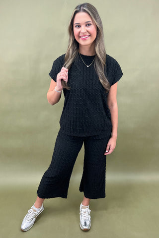 Woman wearing a black outfit with white sneakers on a green background