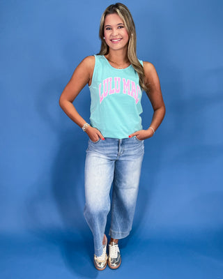 Woman wearing a light blue tank top with 'Louisiana' text and jeans against a blue background