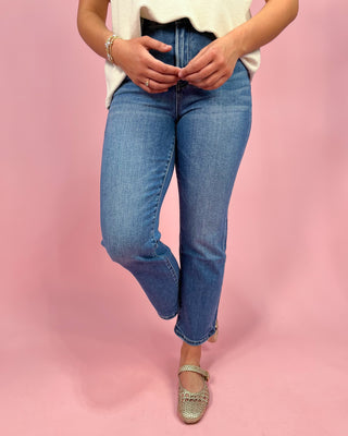 Person wearing blue jeans on a pink background