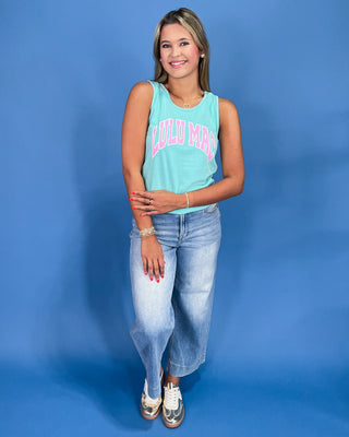 Woman wearing a light blue tank top with text and light blue jeans against a blue background