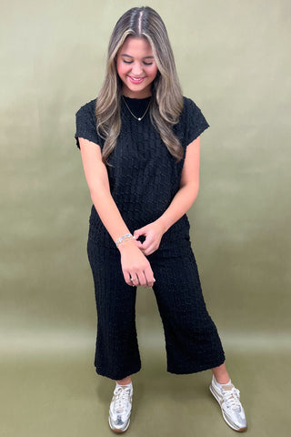 Woman wearing a black outfit with white sneakers on a green background