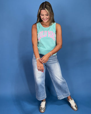 Woman wearing a light blue sleeveless top with 'LULULEMON' text and light blue jeans on a blue background