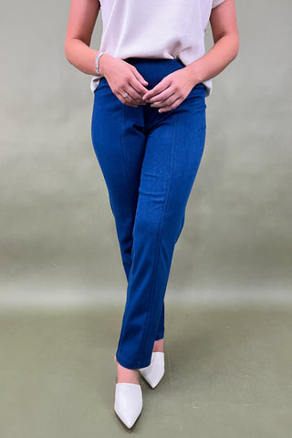 Person wearing blue pants and white shoes on a plain background