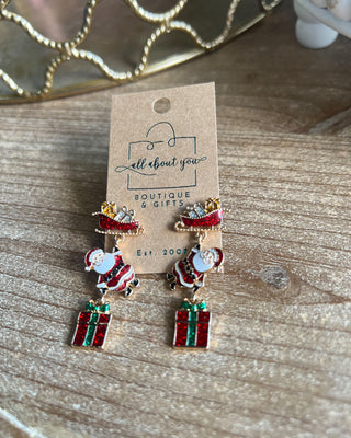 Shop the Christmas Santa Sleigh Earrings at All About You Boutique! Festive glittery Santa, sleigh, and gift dangle earrings perfect for holiday outfits.