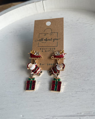 Shop the Christmas Santa Sleigh Earrings at All About You Boutique! Festive glittery Santa, sleigh, and gift dangle earrings perfect for holiday outfits.