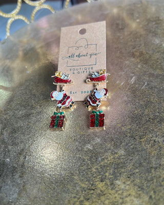 Shop the Christmas Santa Sleigh Earrings at All About You Boutique! Festive glittery Santa, sleigh, and gift dangle earrings perfect for holiday outfits.