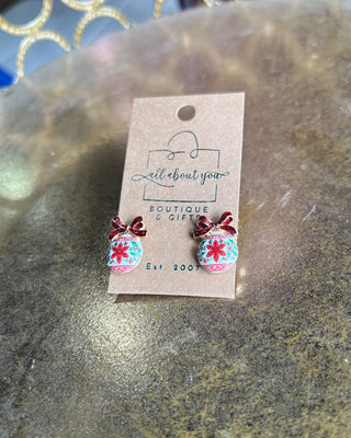 Shop the Christmas Ball Ornament Earrings at All About You Boutique! Festive white ornaments with red glitter bows and floral details. Perfect for holiday outfits.