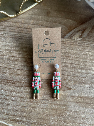 Shop the Nutcracker Pearl Drop Earrings at All About You Boutique! Festive Christmas earrings with faux pearl studs, floral nutcrackers, and gold accents.