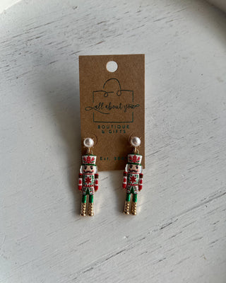 Shop the Nutcracker Pearl Drop Earrings at All About You Boutique! Festive Christmas earrings with faux pearl studs, floral nutcrackers, and gold accents.
