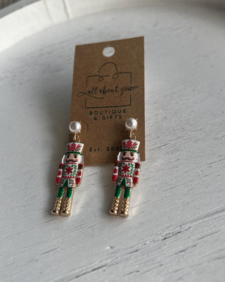 Shop the Nutcracker Pearl Drop Earrings at All About You Boutique! Festive Christmas earrings with faux pearl studs, floral nutcrackers, and gold accents.
