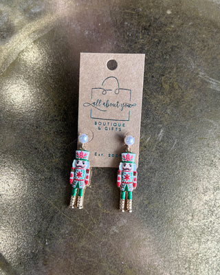 Shop the Nutcracker Pearl Drop Earrings at All About You Boutique! Festive Christmas earrings with faux pearl studs, floral nutcrackers, and gold accents.