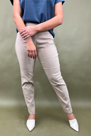 Person wearing beige pants and white shoes on a plain background