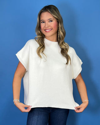 Cream ribbed mock neck short sleeve knit top with relaxed fit and rolled sleeves.