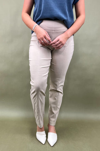 Person wearing beige pants and white shoes on a plain background