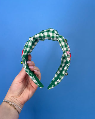Shop the Green Gingham Nutcracker Headband at All About You Boutique! Festive Christmas hair accessory with beaded nutcracker, green rhinestones, and knotted top.