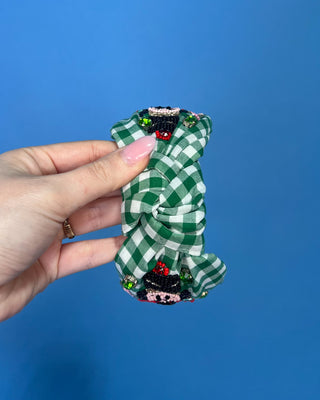 Shop the Green Gingham Nutcracker Headband at All About You Boutique! Festive Christmas hair accessory with beaded nutcracker, green rhinestones, and knotted top.