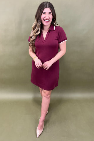 Woman wearing a maroon dress against a plain background