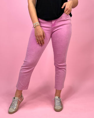 Person wearing pink jeans and a black top on a pink background