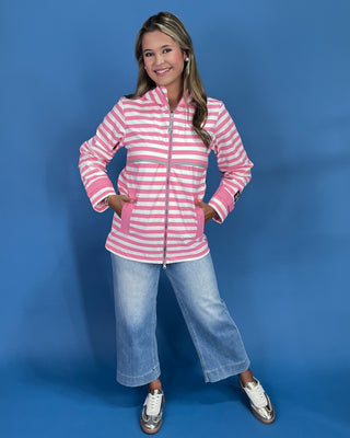 Woman wearing a pink and white striped jacket and blue jeans on a blue background