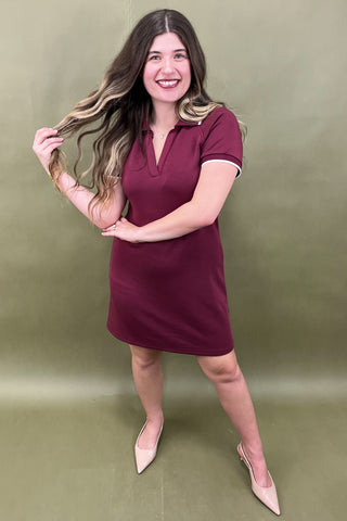 Woman in a maroon dress posing against a green background