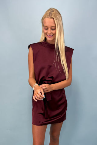 Woman wearing a burgundy dress against a light blue background