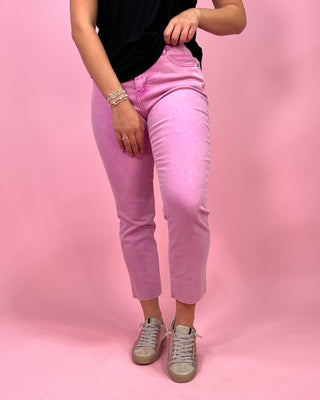 Person wearing pink jeans and a black top on a pink background