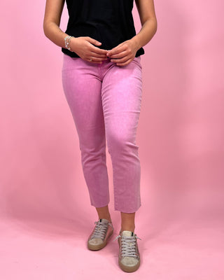 Person wearing pink pants and a black top on a pink background