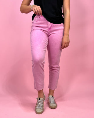 Person wearing pink jeans and a black top on a pink background