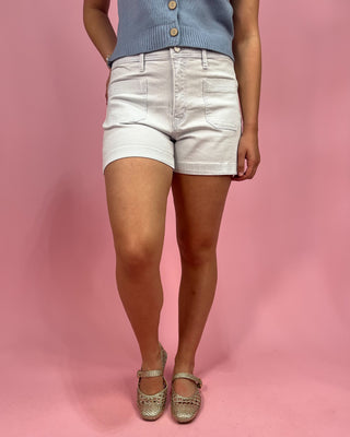 Person wearing light-colored shorts and a blue top on a pink background