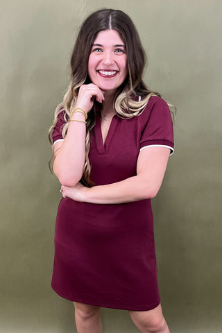 Woman wearing a maroon dress against a green background