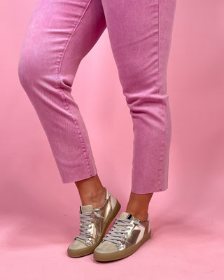 Pink pants and silver high-top sneakers on a pink background
