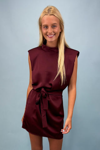 Woman wearing a burgundy dress against a plain background
