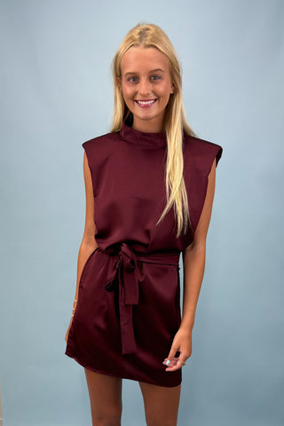 Woman wearing a burgundy dress against a plain background