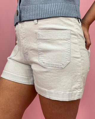 Person wearing light-colored shorts with a pink background