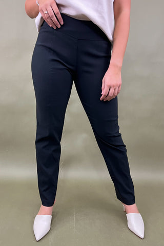 Person wearing navy pants and white shoes on a plain background