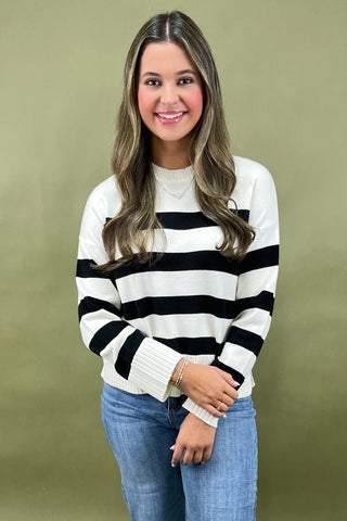 Woman wearing a black and white striped sweater against a green background