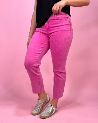 Person wearing bright pink pants and silver shoes on a pink background